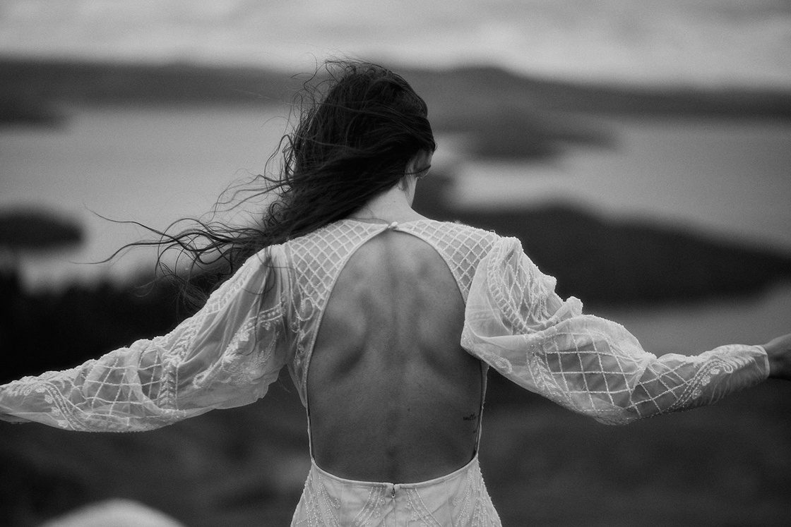 Black and white, open-back lace dress, hair blown by sea wind