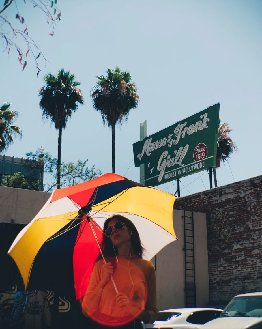 Under a bright umbrella beneath palm trees and a diner sign