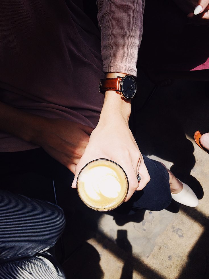 Close detail of a wristwatch while holding a coffee
