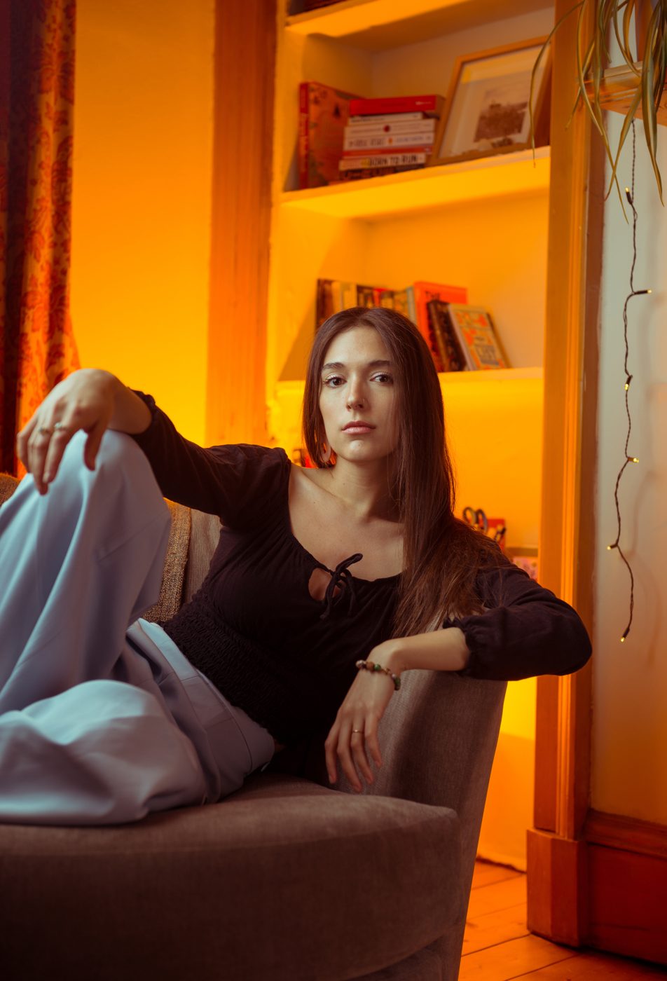 Seated in warm lamplight in a black top
