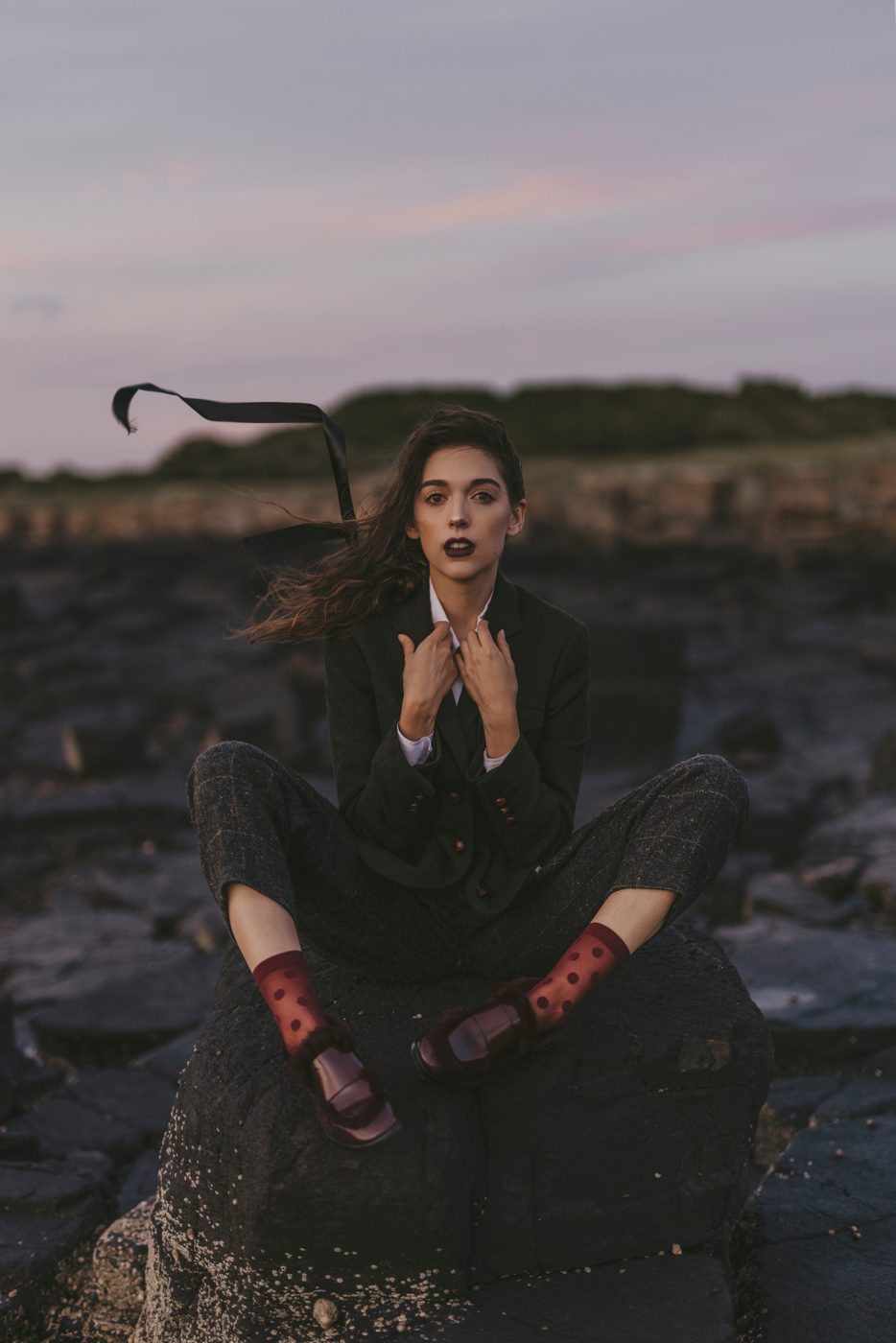 Seated on coastal rocks at dusk